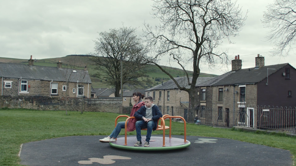 An image from the video wherein the mom and the kid is talking about the dad in the Merry-Go-Round