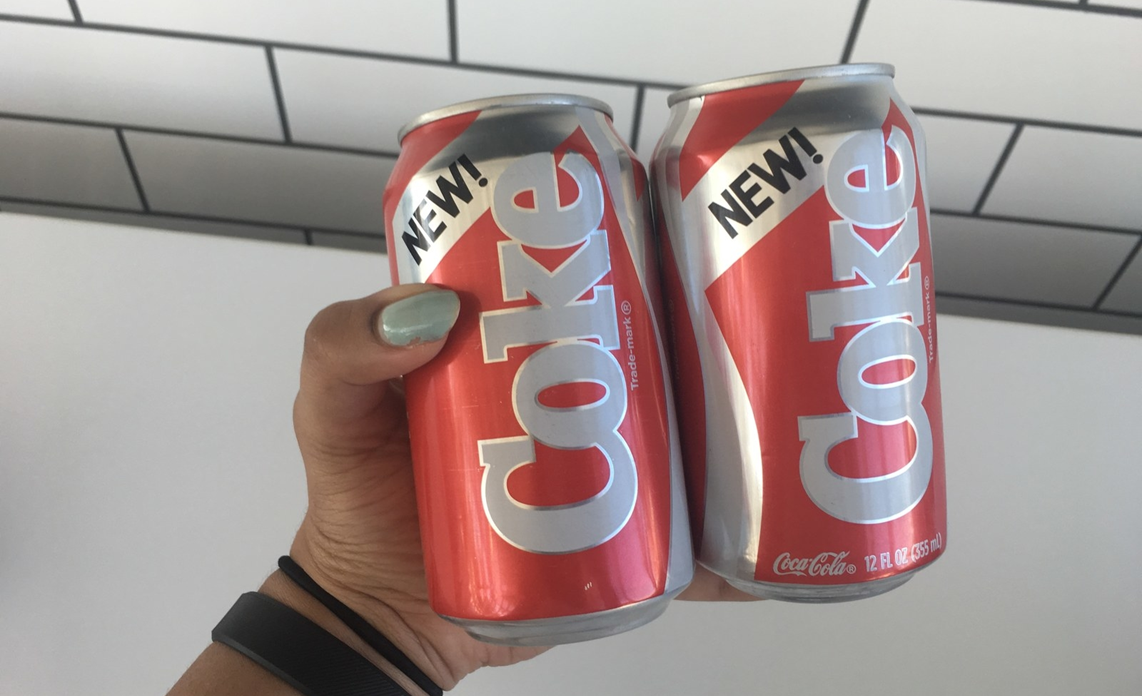 An image of two cans of New Coke being held by a woman
