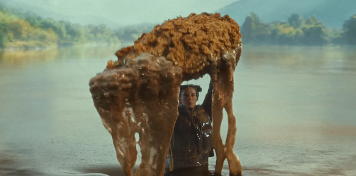 An image from the video wherein a woman is lifting a giant fried chicken while submerged in a lake of gravy